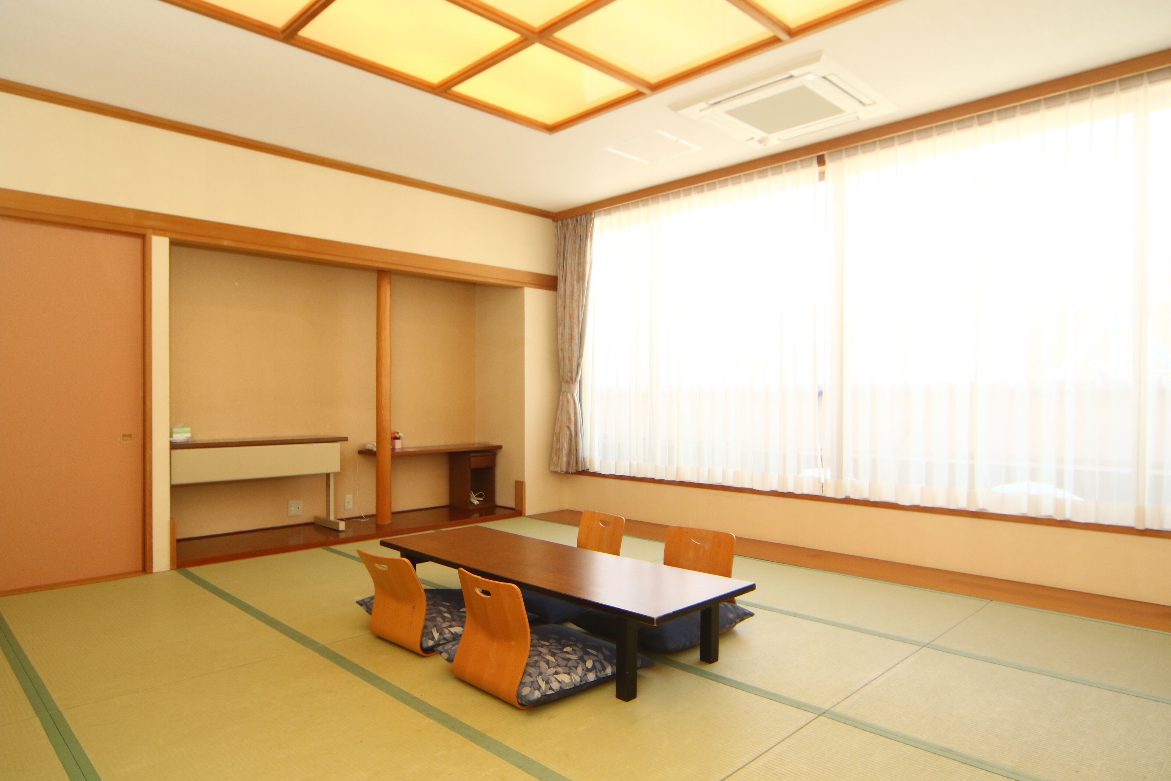 Una habitación tradicional japonesa con suelo de tatami, una mesa baja y puertas correderas.