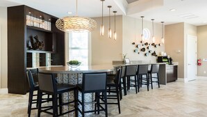 Une cuisine moderne dotée d’un îlot central, de tabourets de bar, de luminaires suspendus et d’un mur décoratif.