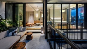 A modern interior with a sofa, coffee table, and a view of a cityscape through large windows.