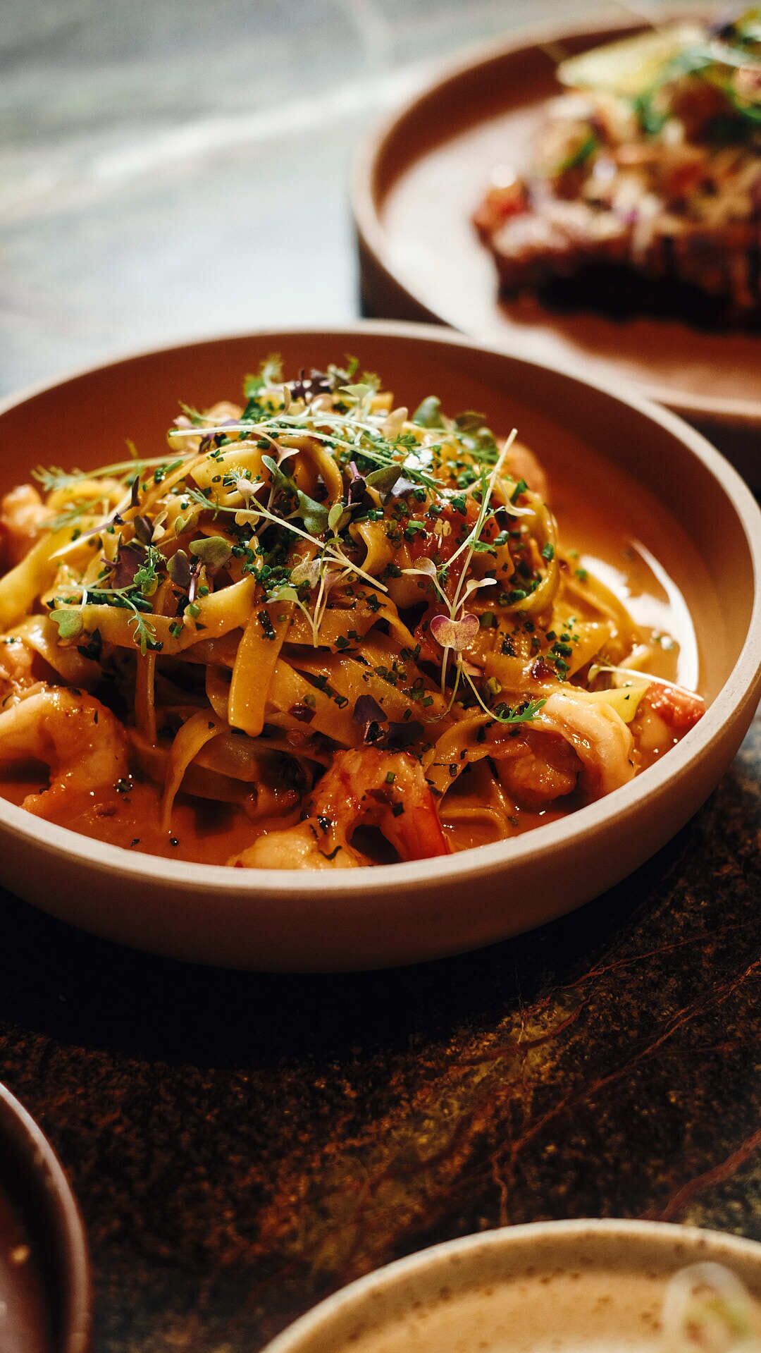Un plato de pasta con salsa de tomate, adornado con microgreens.