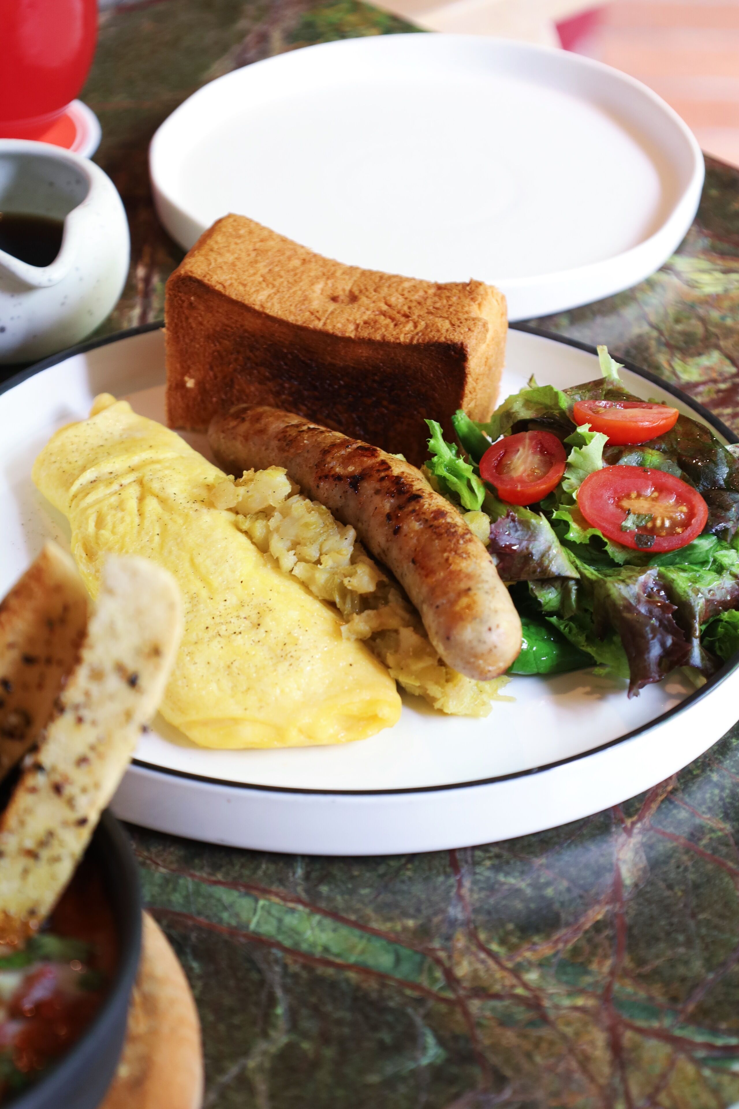 A plate with toast, sausage, scrambled eggs, and a salad.