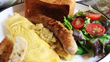 A plate with toast, sausage, scrambled eggs, and a salad.