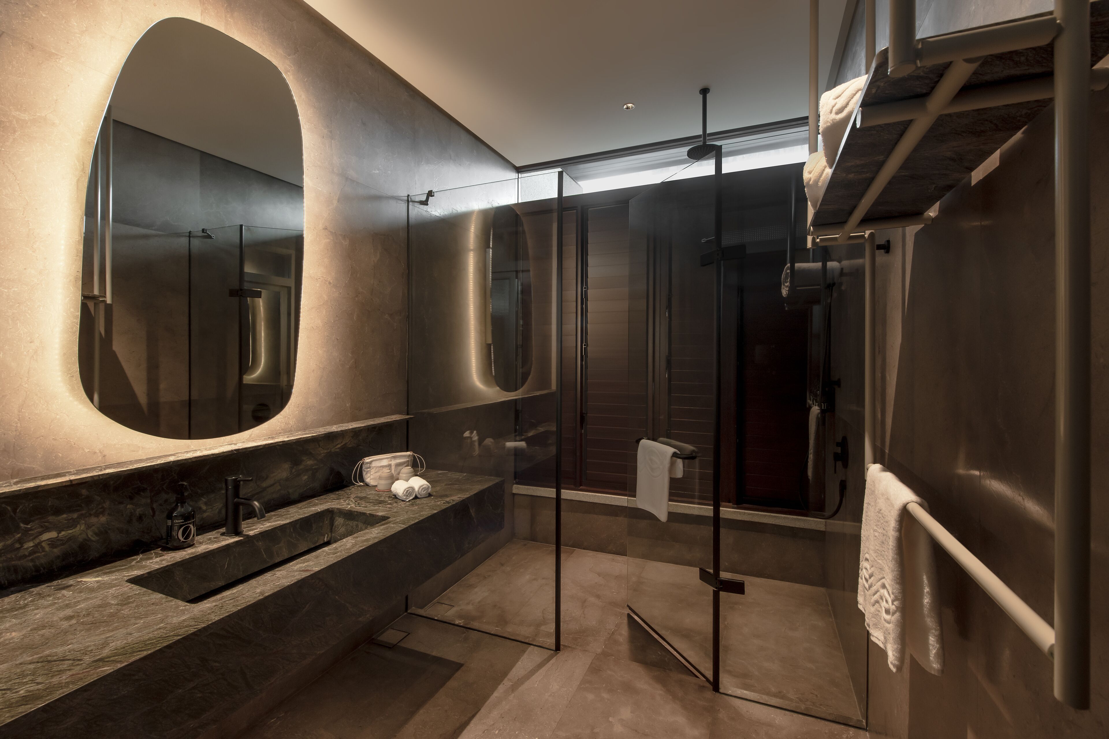 A modern bathroom with a large mirror, a glass shower enclosure, and a built-in sink.