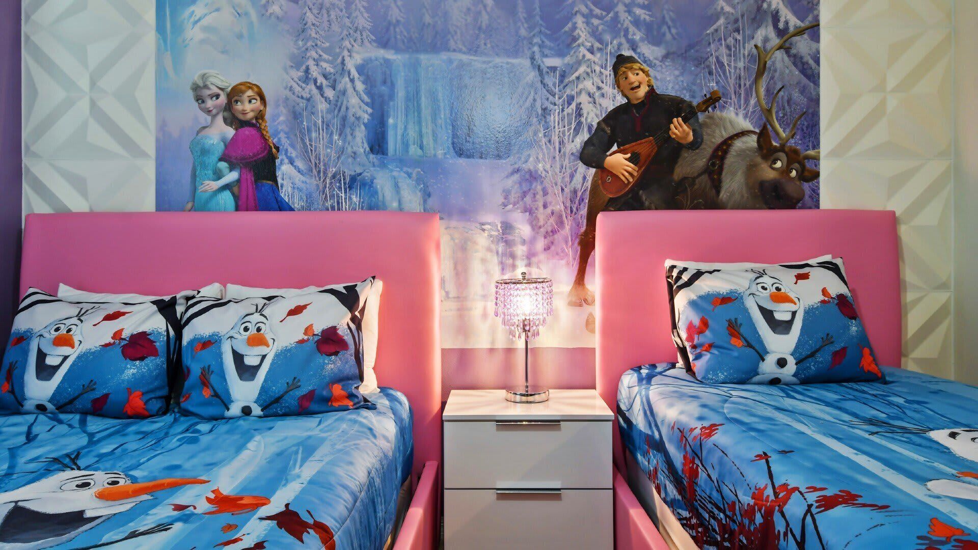 Ein Schlafzimmer mit zwei Betten, jeweils mit Olaf-Mottos, einem Nachttisch mit Lampe und einem Wandbild mit Figuren aus einem Winterfilm.