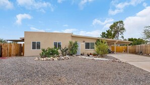 A single-story house with a beige exterior, a covered patio, and a gravel driveway. - Tucson Pool House, a vacation home with easy access to all Tucson offers (Tucson)