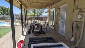 A covered patio with a pool table, chairs, and a flamingo inflatable. - Tucson Pool House, a vacation home with easy access to all Tucson offers (Tucson)
