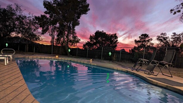 A swimming pool with a wooden deck, surrounded by a fence and trees. - Tucson Pool House, a vacation home with easy access to all Tucson offers (Tucson)