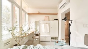 Quarto com cama, escrivaninha, cadeira, guarda-roupa e planta em vaso.