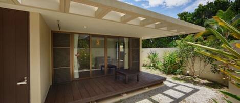 A modern house with a covered patio, large sliding glass doors, and a gravel driveway.