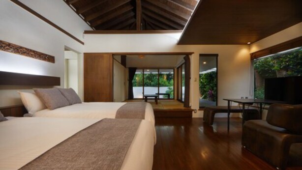 Een moderne hotelkamer met een groot bed, een zithoek en uitzicht op het groen.