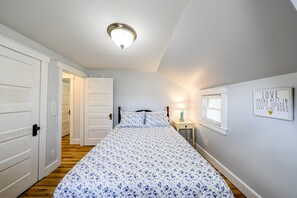 Un dormitorio con una cama, una mesita de noche, un reloj de pared y una puerta.