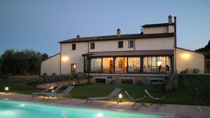 Une maison à deux étages dotée d’une piscine, d’un espace salon extérieur et d’un patio couvert.