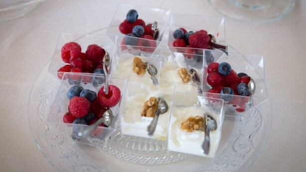 Un plateau de desserts avec des portions individuelles de yaourt, garnies de divers fruits rouges et de noix.