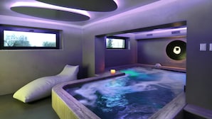 Um espaço de spa com hidromassagem, cadeira de massagem e janela com vista para o exterior.