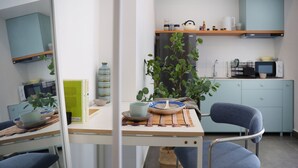 Een moderne keuken met een eethoek, met een houten tafel, blauwe stoelen en een potplant.