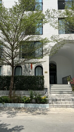 A modern building with a brick facade, large windows, and a central entrance with steps.