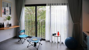 Een klein balkon met een tafel en stoelen, een bloempot en een blauwe fitnessbal.