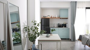 Een moderne keuken met een koelkast, magnetron en een klein eetgedeelte met een tafel en stoelen.