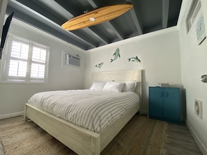 Une chambre à coucher avec un lit, une fenêtre, un ventilateur de plafond et des décorations murales.