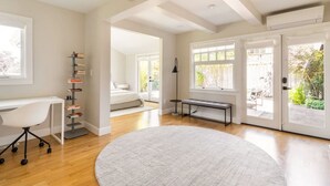 A modern bedroom with a large bed, a desk, and a bookshelf. - Main house at 126 · Modern 2 Bedroom unit in a 1915 Craftsman home (Kirkland)