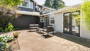 A patio with a sofa and chairs, a small table, and a potted plant. - Main house at 126 · Modern 2 Bedroom unit in a 1915 Craftsman home (Kirkland)