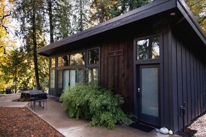 A modern building with a 'Goat Shed' sign, large windows, and a patio area with outdoor seating.
