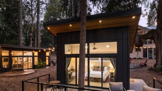 A modern cabin with a deck, large windows, and a dining area. - Panoramic Riverside and Lush Forests Views, Pet Friendly, New Décor, Steps Away From Dockside (West Linn)