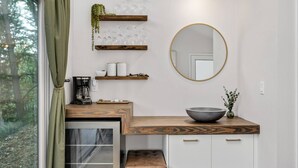A modern kitchen with a wooden countertop, a round mirror, and a coffee maker. - Panoramic Riverside and Lush Forests Views, Pet Friendly, New Décor, Steps Away From Dockside (West Linn)