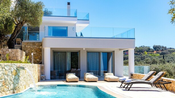 Una casa moderna a due piani con piscina, area relax esterna e vista sul paesaggio circostante.