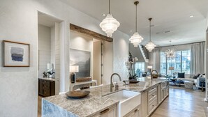 Una cocina moderna con encimera de mármol, armarios de madera e iluminación colgante.