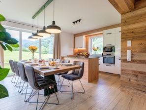 Een moderne keuken met houten kastjes, een centraal eiland en een eethoek met een tafel voor vier personen.