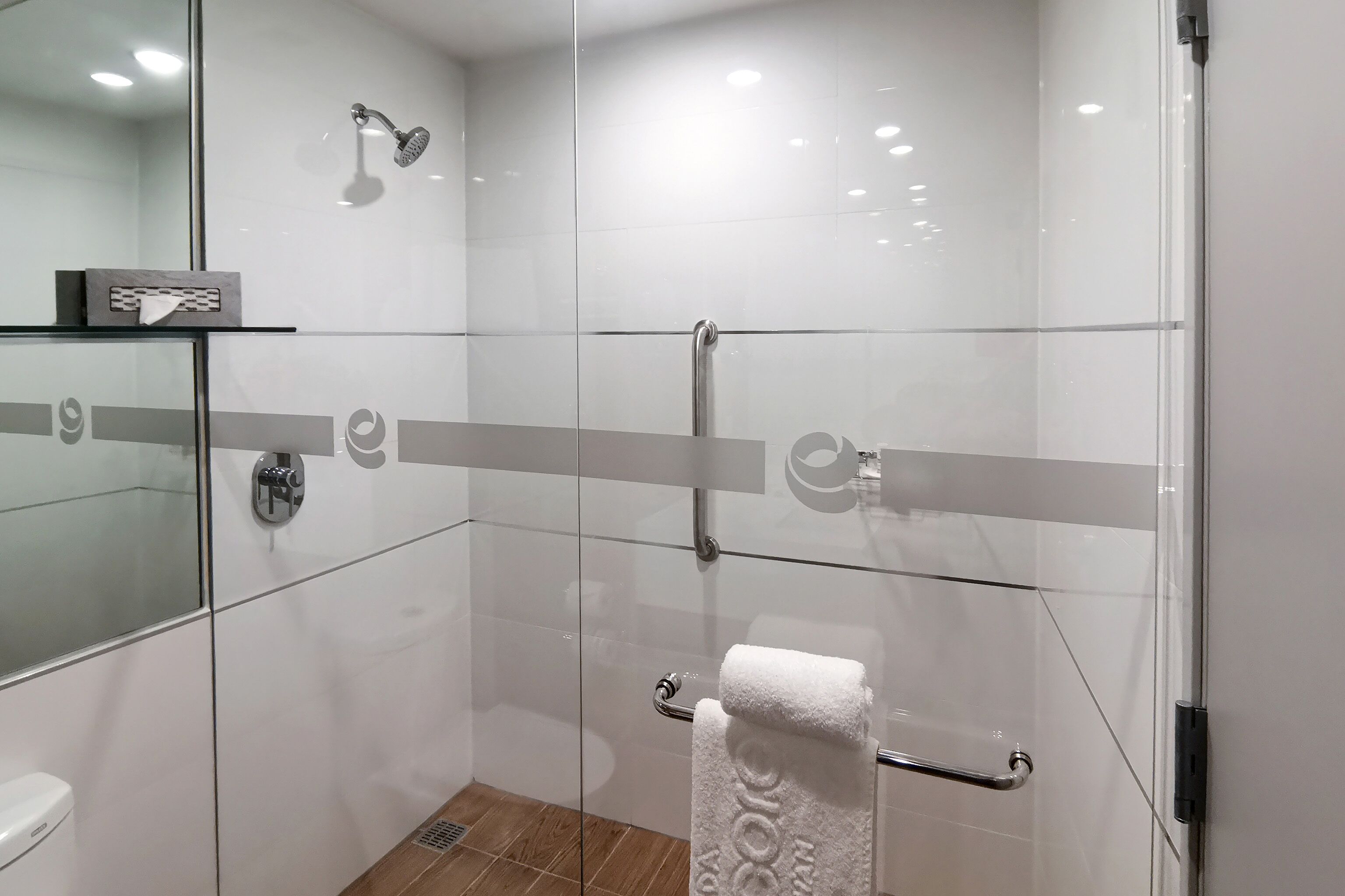 A modern bathroom with a glass shower enclosure, a glass door, and a towel rack.