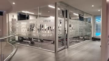 A modern fitness center with glass walls, motivational phrases, and exercise equipment.