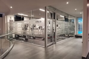A modern fitness center with glass walls, motivational phrases, and exercise equipment. - Ramada Encore by Wyndham Guadalajara Aeropuerto (El Salto)