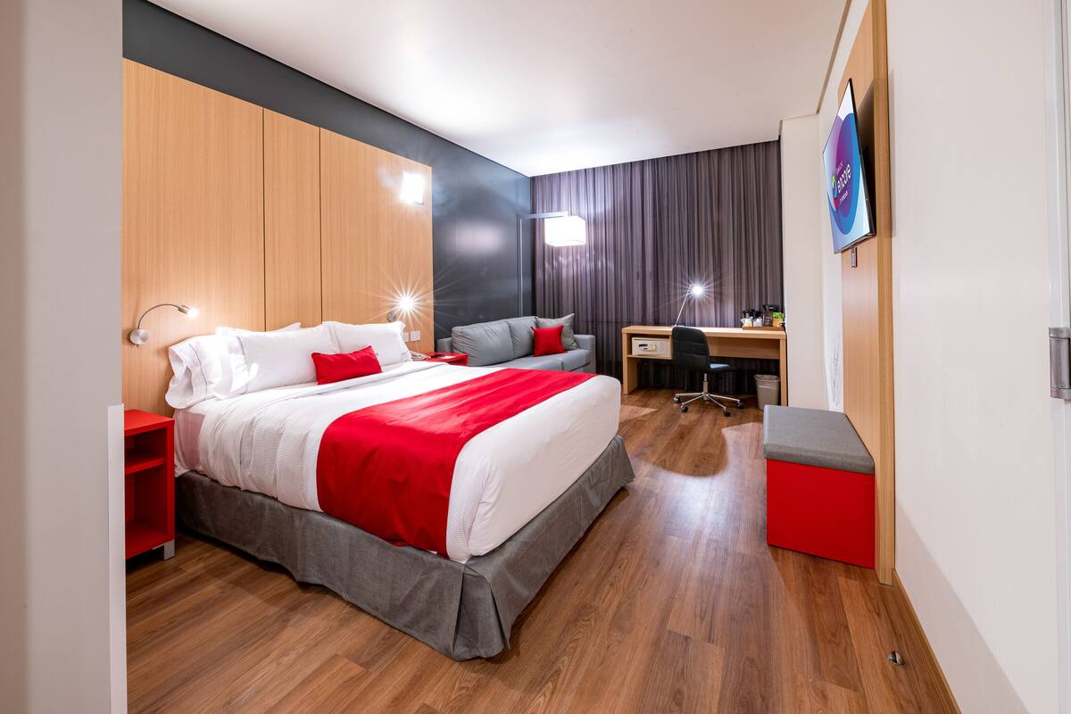 Une chambre d’hôtel moderne avec un grand lit, un bureau et une télévision.