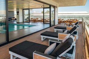 A rooftop pool area with lounge chairs and tables, a swimming pool, and a view of the cityscape. - Ramada Encore by Wyndham Guadalajara Aeropuerto (El Salto)