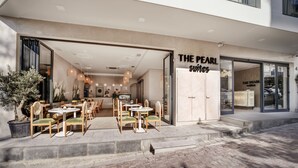An outdoor seating area with tables and chairs, a reception desk, and a building entrance labeled "The Pearl Suites". - The Pearl Suites (Istanbul)