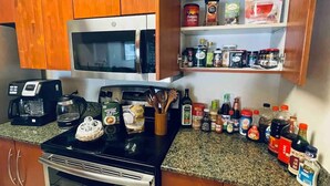 Une cuisine dotée de meubles de rangement en bois, d’un four à micro-ondes, d’une cuisinière et de divers appareils et ustensiles de cuisine.