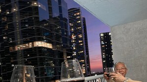Une table à manger, dressée avec de la nourriture et des verres à vin, se détache sur le paysage urbain au crépuscule.