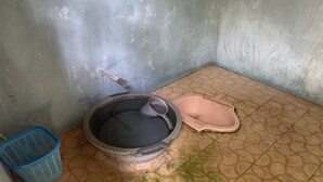 Une petite salle de bain avec un grand lavabo, des toilettes roses et un panier bleu.