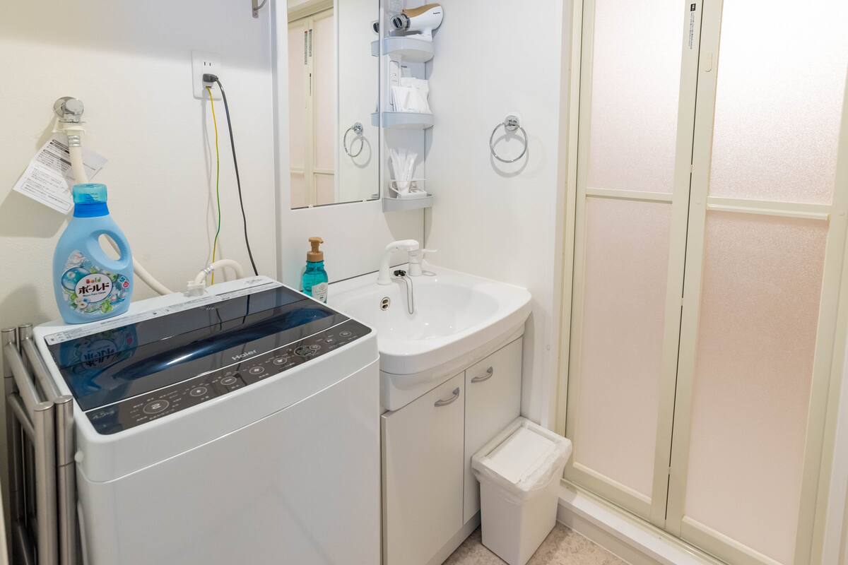 A bathroom with a washing machine, sink, and towel rack.