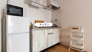 A kitchen with a white refrigerator, wooden cabinets, a countertop with a knife block, and a white cart with shelves.