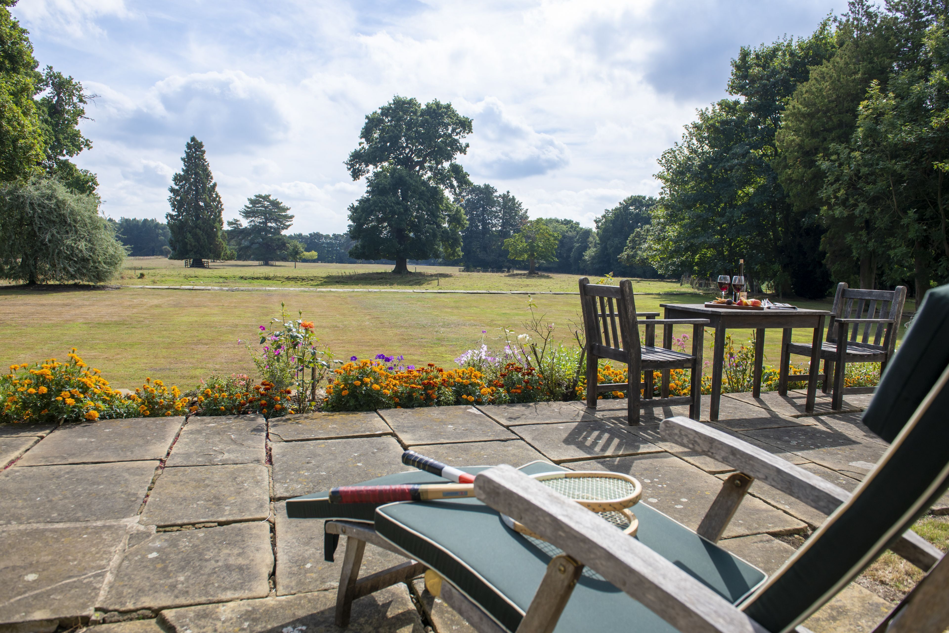 A patio area with outdoor seating, a table, and a view of a grassy field.