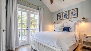 Ein Schlafzimmer mit einem großen Bett, einem Nachttisch, einer Kommode und einem Deckenventilator.