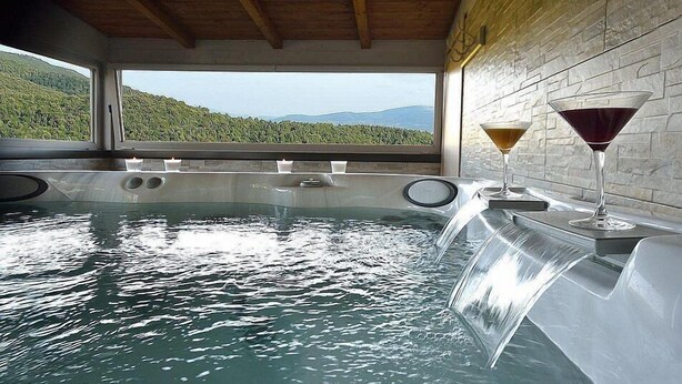 A hot tub with a view of a mountainous landscape, two glasses of wine, and a wooden ceiling. - Villa Sonia M: A characteristic and welcoming cottage located in an isolated position, on the slopes of a hill which is covered with olive groves, with Free WI-FI. (Gualdo Cattaneo)