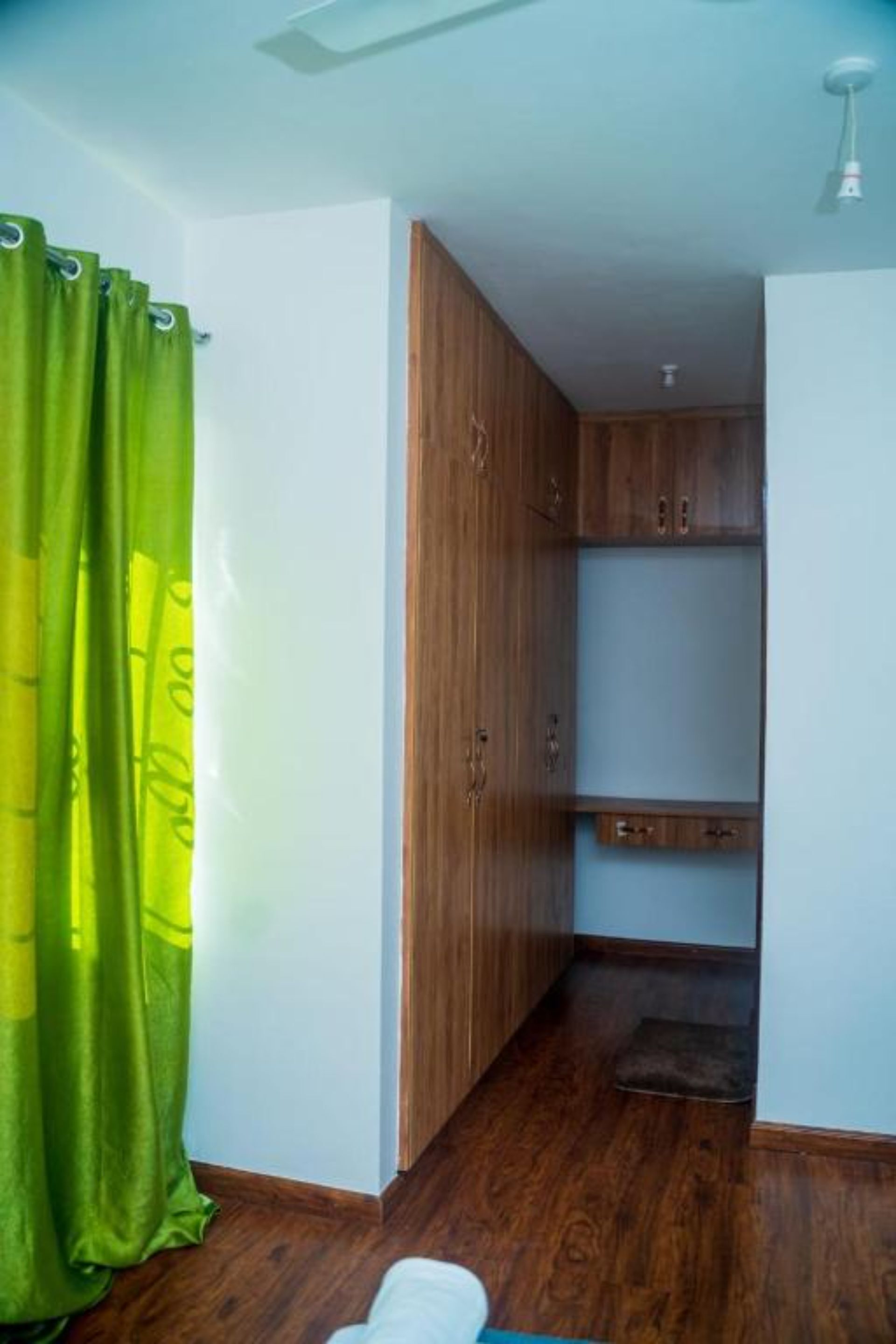 Una habitación con armarios de madera, una cortina verde y suelo de madera.