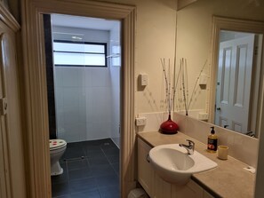 A bathroom with a toilet, sink, mirror, and a window. - The Atrium - Classic Villa with up to 6 Bedrooms (Port Pirie)
