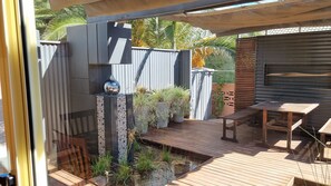 A wooden deck with a small water feature, potted plants, and a seating area. - The Atrium - Classic Villa with up to 6 Bedrooms (Port Pirie)