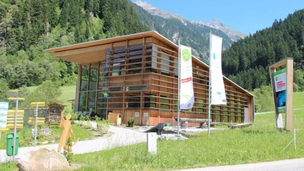 A modern building with a sloped roof, large windows, and multiple banners. - Haus Goldmann by Interhome (Ginzling)