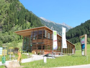 A modern building with a sloped roof, large windows, and multiple banners. - Haus Goldmann by Interhome (Ginzling)